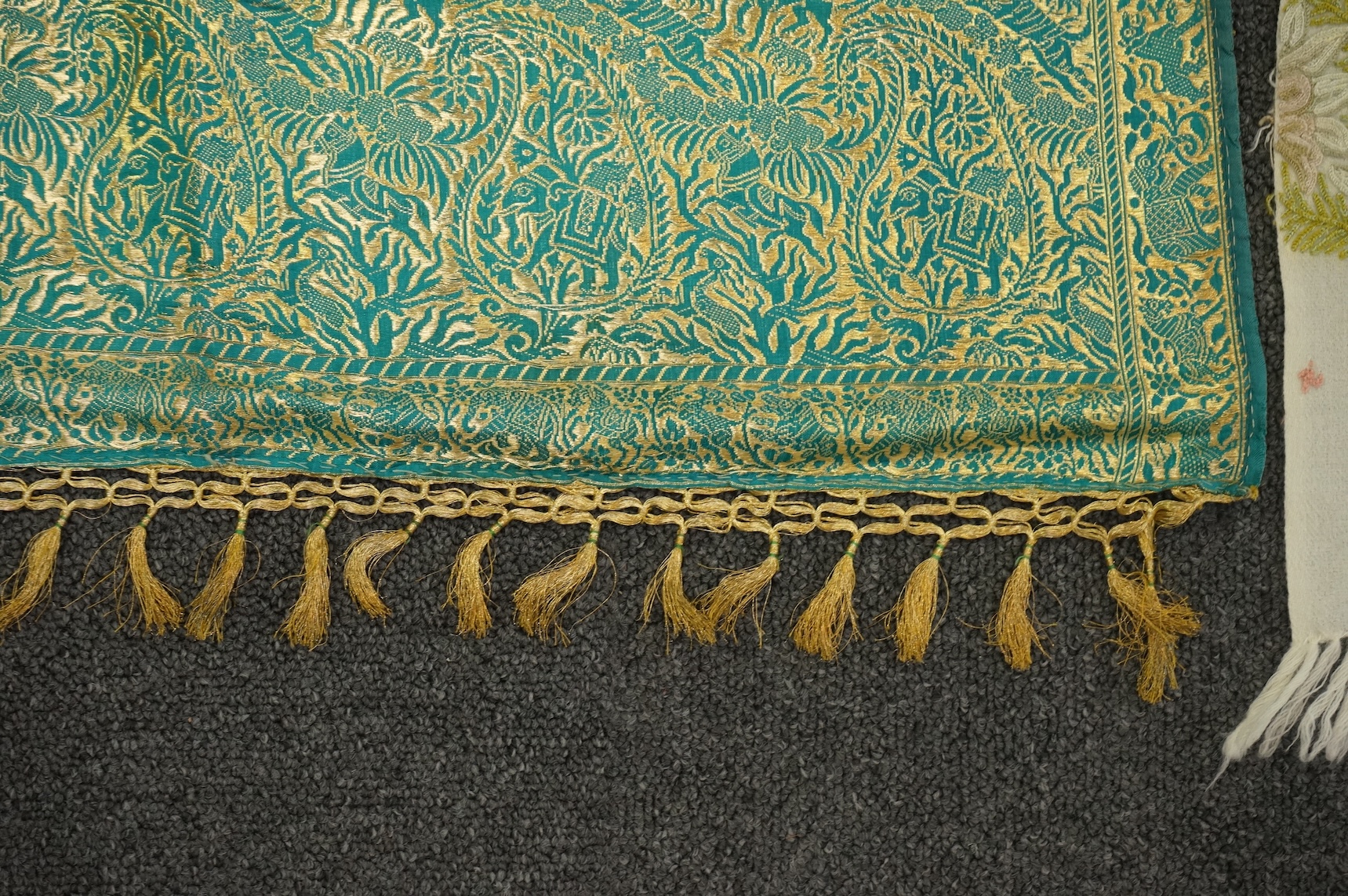 An Indian green and gold silk hand woven brocade stole, a cream pashmina embroidered stole and a similar finely woven and embroidered lilac stole (3). Brocade stole 38cm x 180cm., Condition - light stain to finely woven
